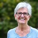 Portrait of Elara Vance, a smiling woman with glasses and a friendly demeanor in a natural garden setting.